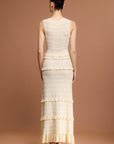 Woman wearing a Sandro sleeveless, tiered dress with a beige and white layered knit maxi dress
