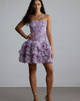 Woman wearing a purple strapless 3d floral dress with floral patterns against a plain background