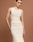 Woman wearing a Sandro sleeveless, tiered dress with a beige and white layered knit maxi dress