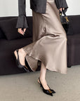 Person wearing a satin skirt and black shoes in an indoor setting