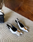White high-heeled shoes with gold accents slingack sandals