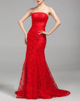 Woman wearing a strapless red lace evening gown on a gray background