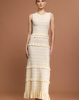 Woman wearing a Sandro sleeveless, tiered dress with a beige and white layered knit maxi dress