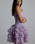 Woman wearing a purple 3d floral dress against a gray background