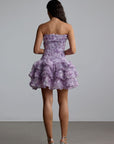 Woman wearing a purple strapless 3d floral dress with floral patterns against a plain background