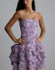 Woman wearing a purple strapless 3d floral dress with floral patterns against a plain background