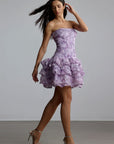 Woman wearing a purple strapless 3d floral mini dress with ruffle patterns against a plain background