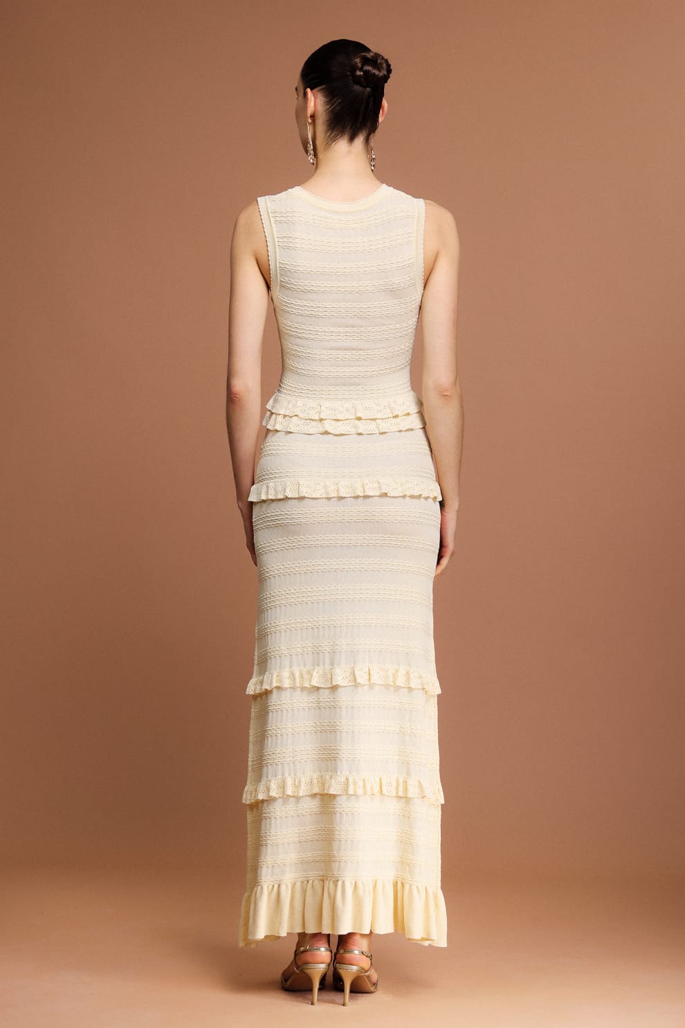 Woman wearing a Sandro sleeveless, tiered dress with a beige and white layered knit maxi dress