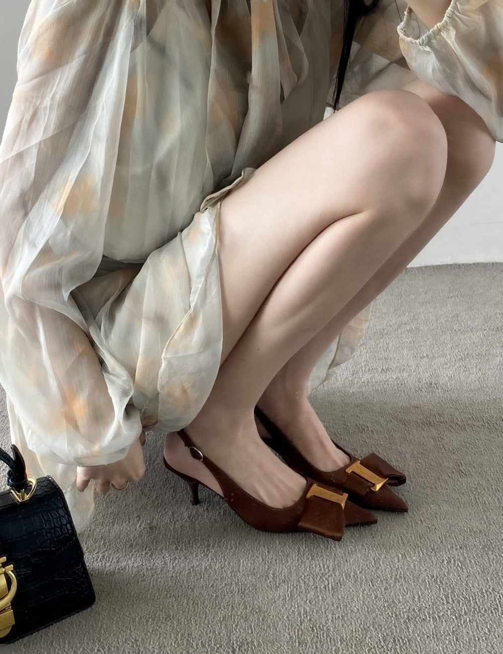 Person wearing brown high-heeled shoes with gold accents kitten heels.
