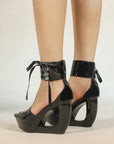 Sculptural cut-out wedge platform heels in glossy black patent finish.