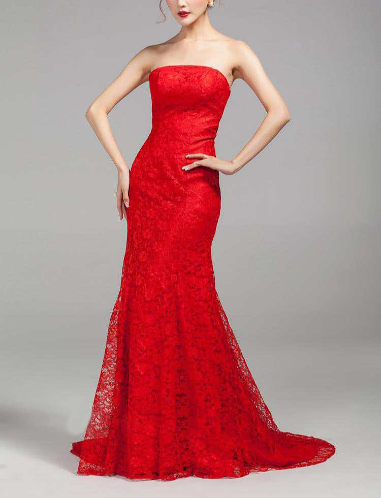 Woman wearing a strapless red lace evening gown on a gray background
