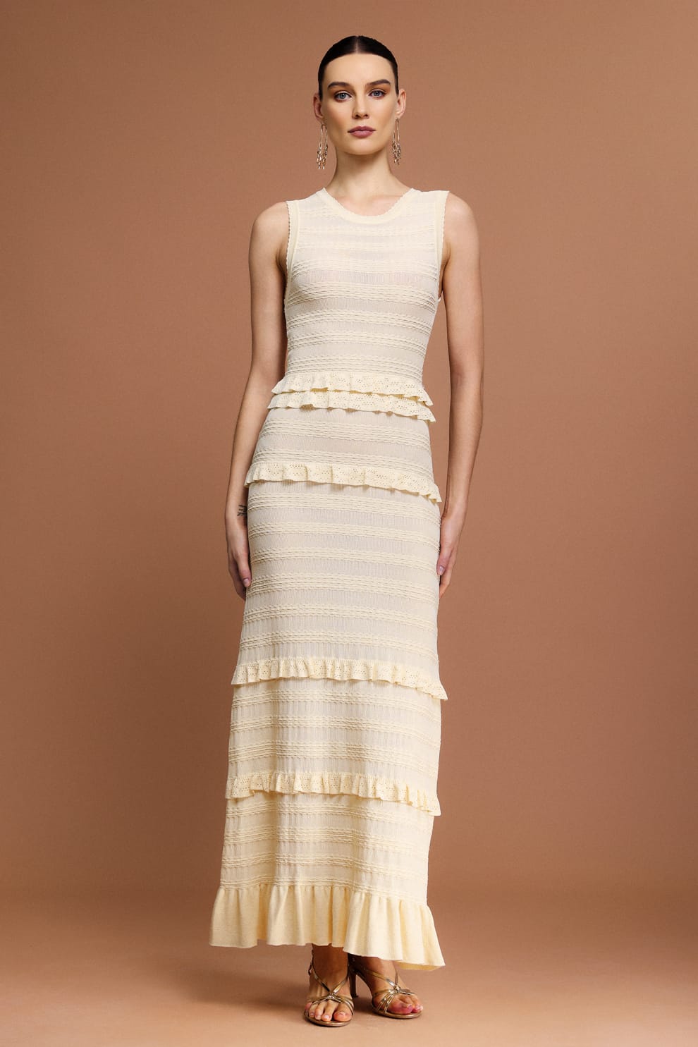 Woman wearing a Sandro sleeveless, tiered dress with a beige and white layered knit maxi dress