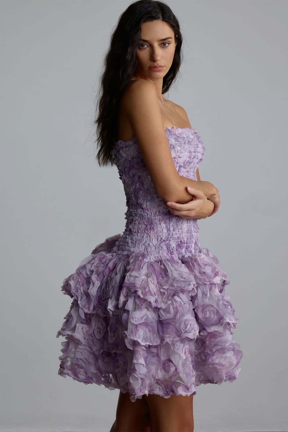 Woman wearing a purple 3d floral dress against a gray background