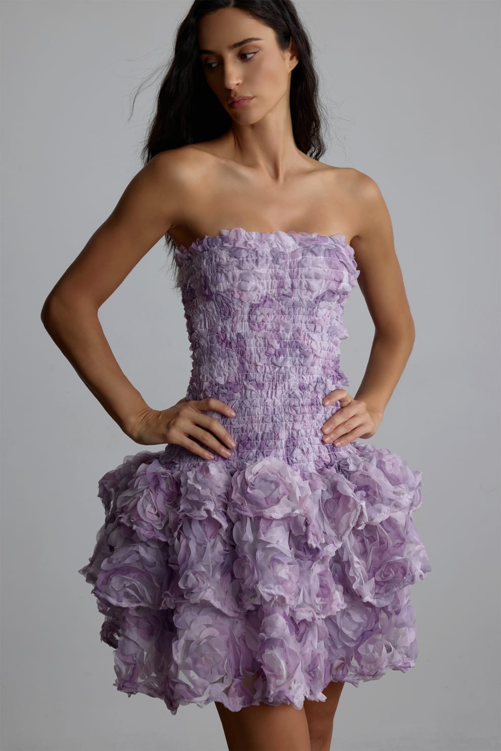 Woman wearing a purple strapless 3d floral dress with floral patterns against a plain background